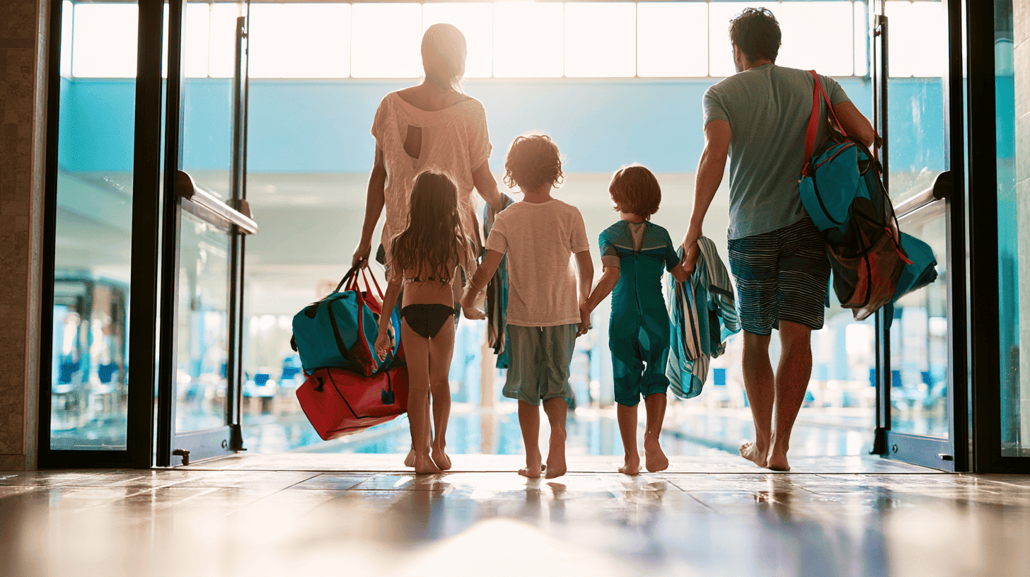Gezin met drie kinderen loopt met zwemtassen en handdoeken naar de ingang van een zwembad